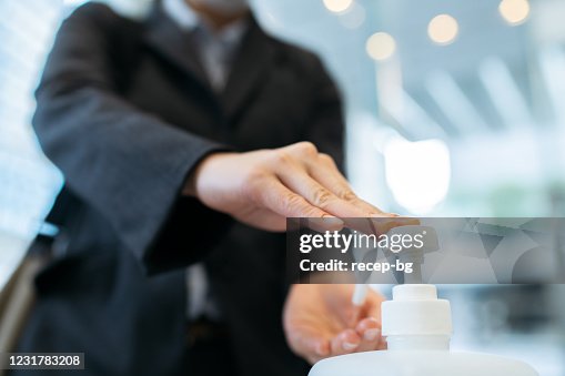 オフィスビルのエントランスホールでアルコールハンド消毒剤を塗布するビジネスウーマンの写真をクローズアップ オフィスビルのエントランスホールでアルコールハンド消毒剤を塗布するビジネスウーマンの写真をクローズアップ