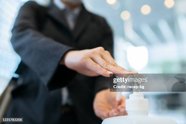 close-up foto de empresária aplicando desinfetante para mão de álcool no hall de entrada do prédio do escritório - hand sanitiser - fotografias e filmes do acervo