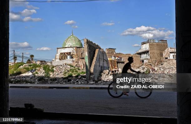 An Iraqi youth rides a bicycle past the Nuri mosque in the old town of the northern city of Mosul, a site heavily damaged by Islamic State group...