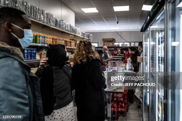 Students wait in line during a food distribution to students in need in Mourad Slimani's butcher shop in Venissieux, on March 18, 2021. - By...