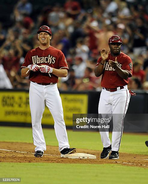 First Base Coach Eric Young of the Arizona Diamondbacks congratulates Sean Burroughs as he smiles at the bench after getting a pinch hit against the...