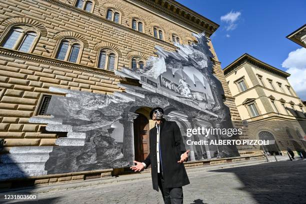 French artist JR poses during the unveiling of his visual installation "La Ferita" on the facade of the Renaissance Palazzo Strozzi in Florence on...