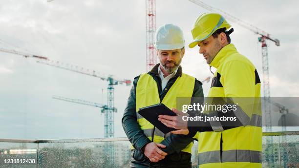 ingenieure arbeiten mit einem tablet auf der baustelle - baustelle stock-fotos und bilder