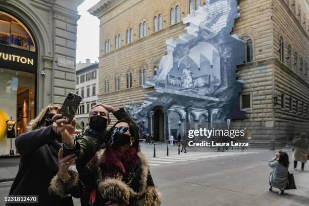 People take a selfie in front of the facade of Palazzo Strozzi with installation by artist JR The Wound at Palazzo Strozzi on March 19, 2021 in...