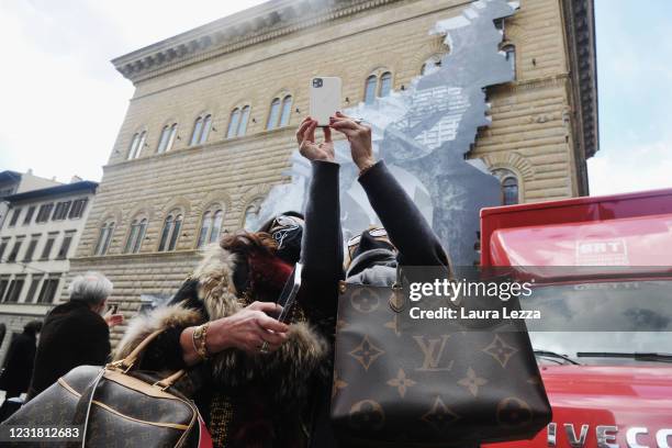 People take a selfie in front of the facade of Palazzo Strozzi with installation by artist JR The Wound at Palazzo Strozzi on March 19, 2021 in...