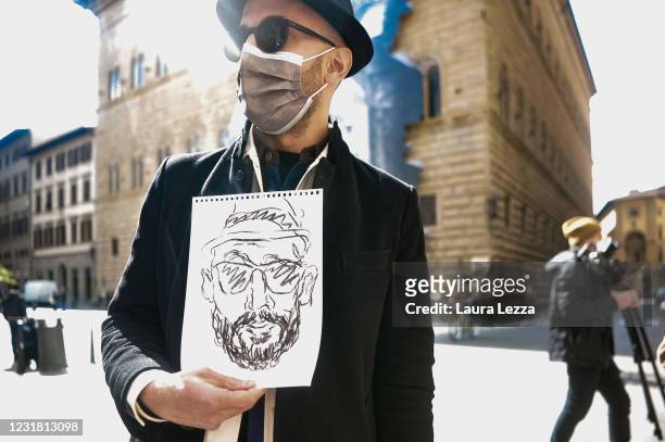 Artist JR poses for a photo in front of the facade of Palazzo Strozzi with his installation The Wound at Palazzo Strozzi on March 19, 2021 in...