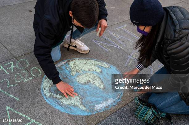 Climate change activists of 'Fridays for Future' group painting the Earth with chalks during a protest in front of the Spanish Parliament calling for...