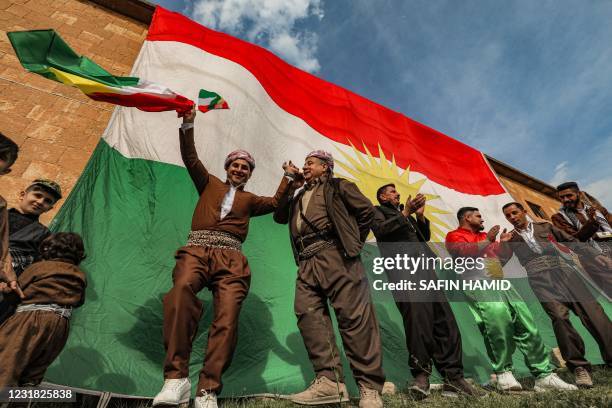 Iraqi Kurds stand before a giant Kurdish flag unfurled along the side of a building as they gather to celebrate Nowruz , the Persian New Year, in the...