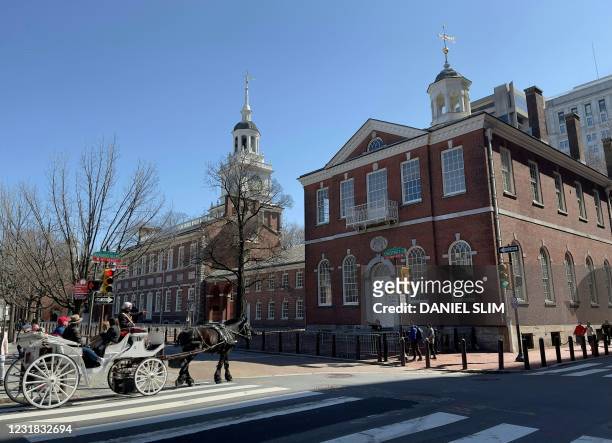 Tourists stop by the Independence Hall in Philadelphia, Pennsylvania, on March 20, 2021.