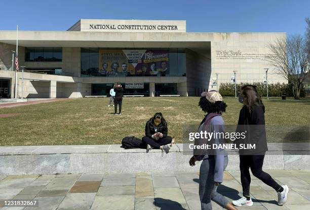 Tourists walk outside the National Constitution Center in Philadelphia, Pennsylvania, on March 20, 2021.