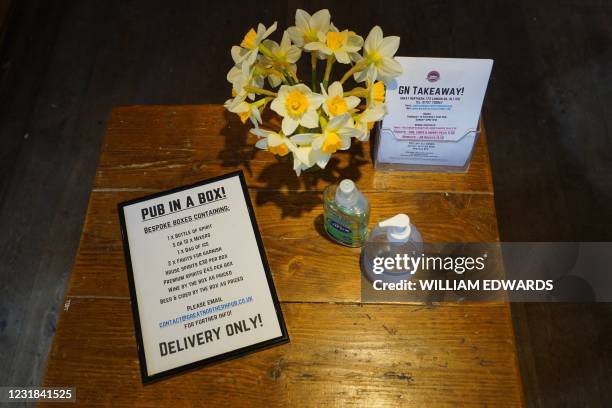 Sign advertising a food delivery service is pictured on a table inside the Great Northern pub in St Albans, north of London on March 18, 2021. - Pots...