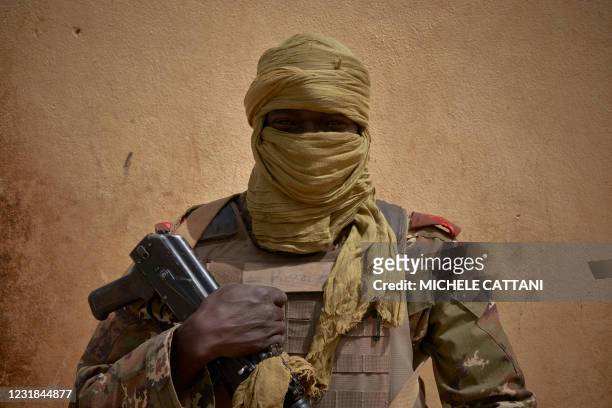 Malian soldier stands posing by the river bank in Konna on March 20, 2021 as the Malian Prime Minister and his delegation visit the town in central...
