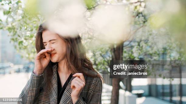 frühlingsallergie. frau niest auf der stadtstraße - frühling pollen stock-fotos und bilder