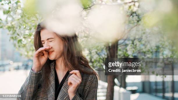 春季過敏。女人在城市街道上打噴嚏 - sneezing 個照片及圖片檔