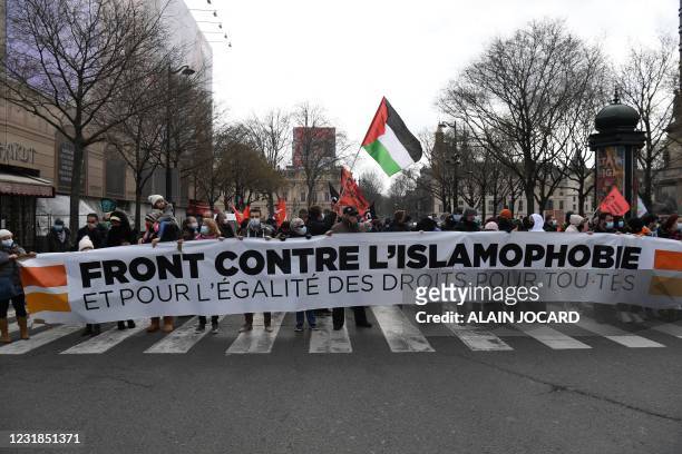 Protesters hold a banner during a demonstration against a bill dubbed as "anti-separatism" and islamophobia in Paris on March 21, 2021. The banner...