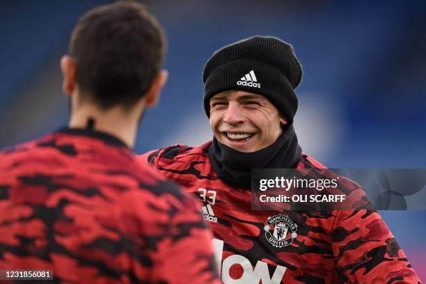 Manchester United's English defender Brandon Williams shares a joke with Manchester United's Portuguese midfielder Bruno Fernandes as they warm up...