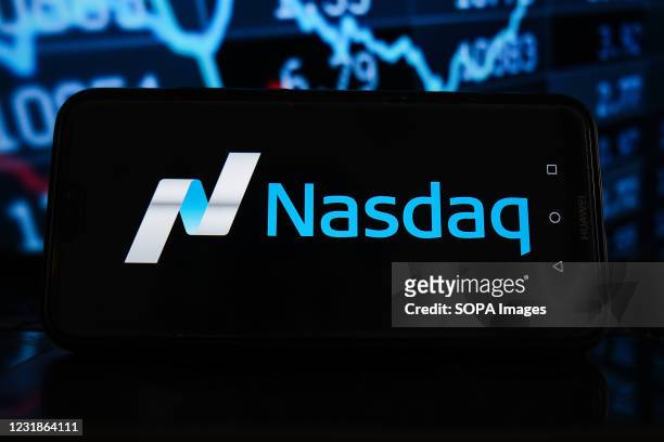 In this photo illustration a Nasdaq logo seen displayed on a smartphone with stock market percentages in the background.