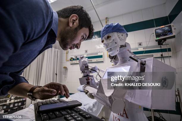 Mahmoud el-Komy, a mechatronics engineer, examines code on a screen on his self-funded prototype for the CIRA-03 remote-controlled robot to assist...