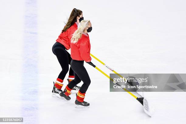 Calgary Flames ice crew members shovel snow during the second period of an NHL game where the Calgary Flames hosted the Edmonton Oilers on March 17...
