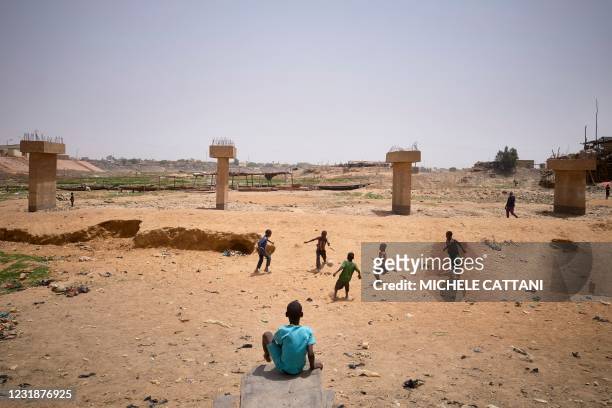 Children play football in the dried river bed in Mopti on March 19, 2021. - Situated In the Inner Niger Delta region of Mali, Mopti lies between the...
