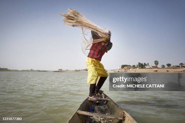 Fisherman on his pirogue throws a net in the Niger river in Mopti on March 17, 2021. - Representing one of the country's main economic sources,...