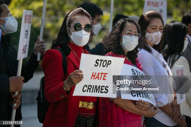 Asian community members hold signs calling for hate to stop at news conference organized to take a unified stand opposing hate crimes against members...