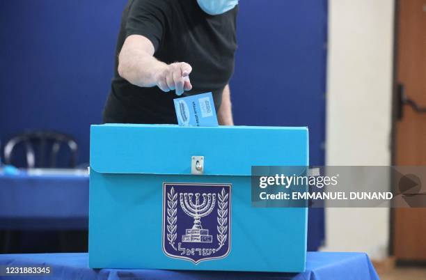 An Israeli woman, wearing a mask for protection against the COVID-19 pandemic, casts her vote on March 23, 2021 at a polling station in Jerusalem in...