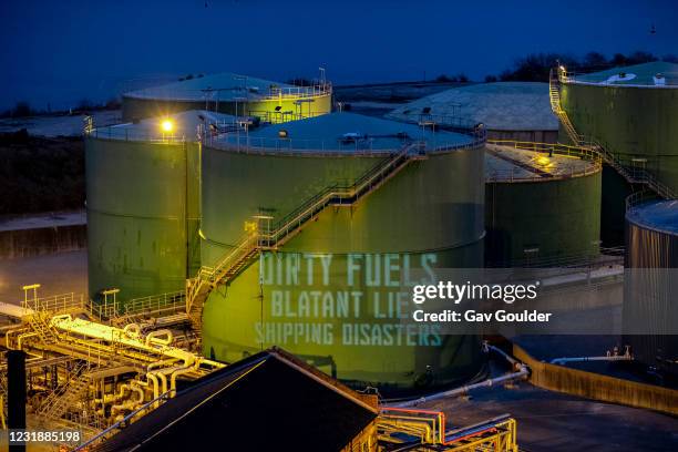 Ocean Rebellion protest in Falmouth Harbour in Cornwall at sun down by projecting slogans and messages onto fuel silos calling for the shipping...