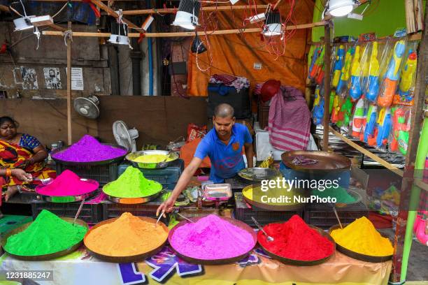 Shop owner organizing various color powder or Gulal for sale ahead of Holi festival , at a market place in Kolkata , India , on 22 March , 2021.