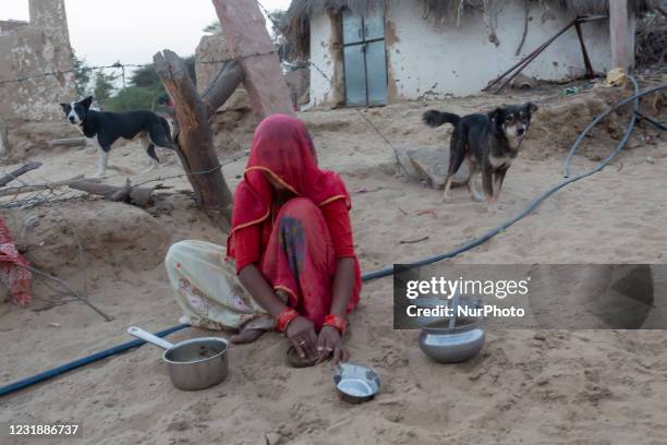 With less rainfall and water at scarce in the arid region of Thar desert, an Indian woman cleaning dishes with sand at Godu village, around 200 kms...