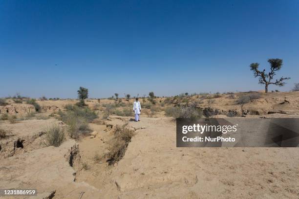 With less rainfall and water at scarce in the arid region of Thar desert, an Indian man stands near the catchment area at Godu village, around 200...