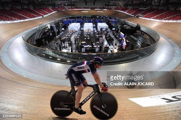 Cycling French team member trains on a track as patients wait prior being vaccinated with Moderna Covid-19 vaccine in the velodrome national used as...