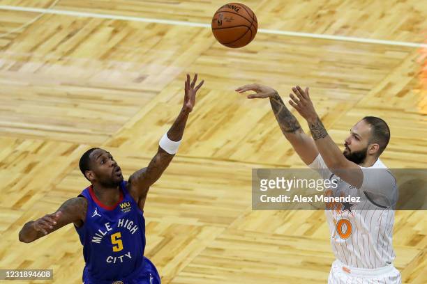 Evan Fournier of the Orlando Magic shoots over Will Barton of the Denver Nuggets during the first half at Amway Center on March 23, 2021 in Orlando,...