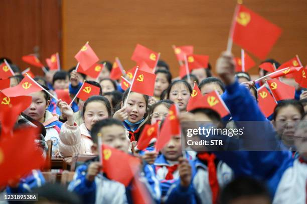 This photo taken on March 23, 2021 shows students waving flags of the Communist Party as they prepare to watch a movie "The Founding of a Party" in...