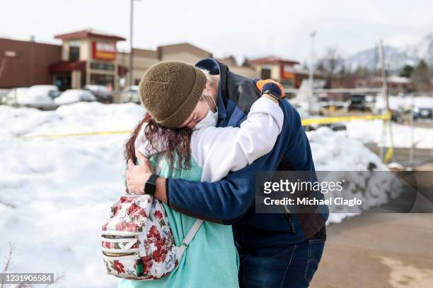 King Soopers employee Brenda Bustamante, left, hugs her coworker Logan Smith, who was inside the grocery store during the attack, at a makeshift...