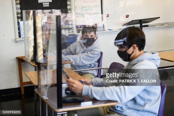 Students sit behind barriers and use tablets during an in-person English class at St. Anthony Catholic High School during the Covid-19 pandemic on...