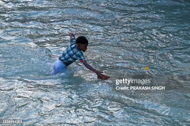 In this picture taken on March 11 a boy catches offerings thrown by Hindu devotees in Ganges river after performing religious rituals during the...