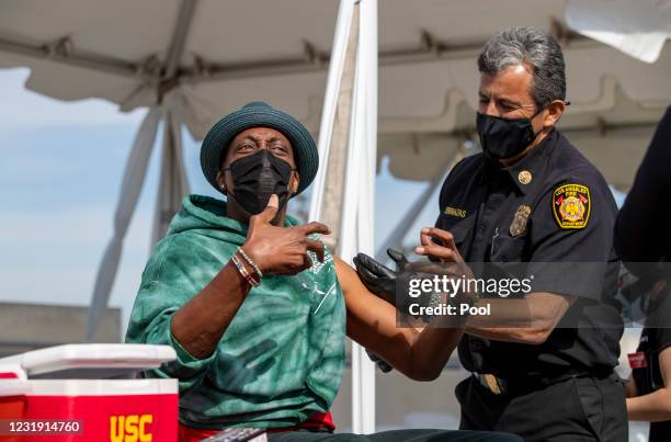 Arsenio Hall reacts after getting a vaccine shot from Los Angeles Fire Chief Ralph Terrazas on the rooftop of parking structure at USC as a part of a...