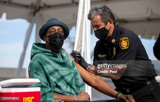 Los Angeles Fire Chief Ralph Terrazas gives a vaccine shot to Arsenio Hall on the rooftop of parking structure at USC as a part of a vaccination...