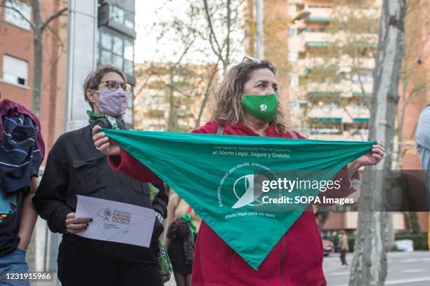 Woman wears a face mask and a scarf from the Argentine pro aborto movement, campaigning for the right to legal, safe and free abortion. A group of...