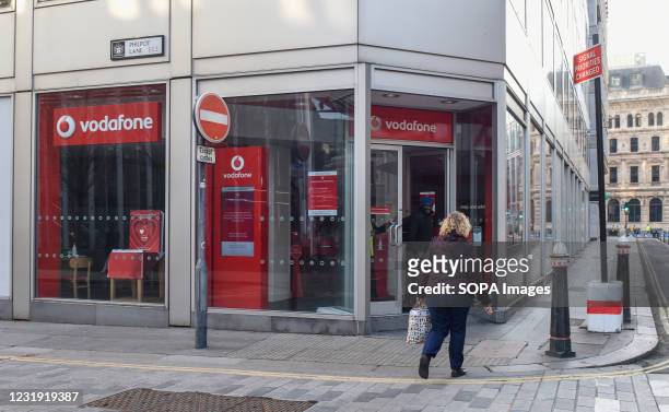 Woman walks past a Vodafone branch seen in central London, Philpot Lane.
