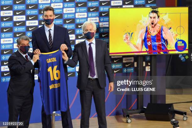 Spanish pivot Pau Gasol holds his new vest with FC Barcelona president Joan Laporta and the club's responsible for the basketball section Josep...