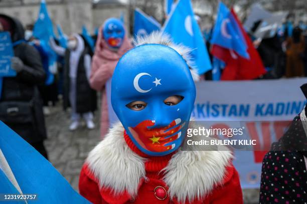 Child from the Uyghur community living in Turkey wears a mask during a protest against the visit of China's Foreign Minister to Turkey, in Istanbul...
