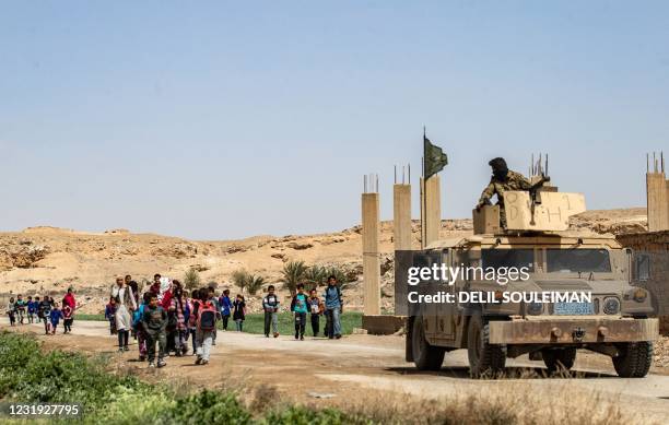 Fighters of the Kurdish-led Syrian Democratic Forces stand guard as students return home from school in the village of Baghouz in Syria's northern...