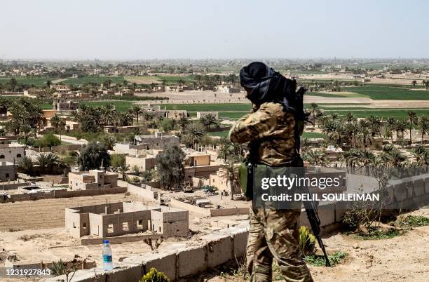 Fighter with the Kurdish-led Syrian Democratic Forces stands guard on a hilltop overlooking the village of Baghouz in Syria's northern Deir Ezzor...