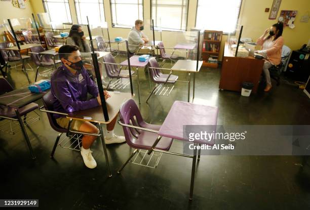 High School senior Victor Gomez, III is surrounded by plexiglass in his Psychology class taught by teacher Raquel Wright as students return to...
