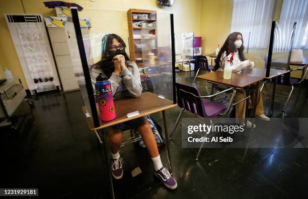 Students Angelica Brown, left, and Goretti Hernandez, right, are surrounded by plexiglass in the classroom of algebra teacher Steven Baker as...