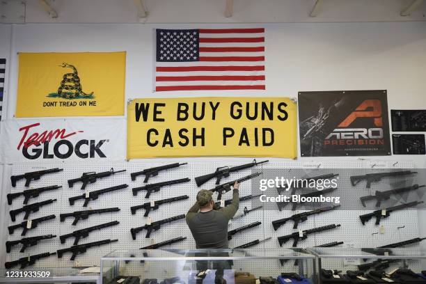 Salesperson takes an AR-15 rifle off the wall at a store in Orem, Utah, U.S., on Thursday, March 25, 2021. Two mass shootings in one week are giving...