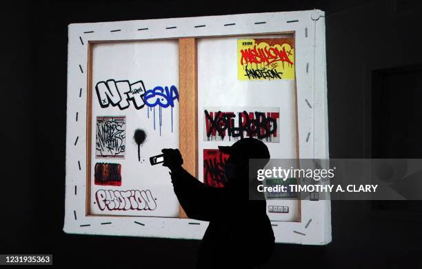 Person takes a photo in front of a piece by Mashkow, during a press preview on March 25, 2021 of the grand opening of Superchief Gallery NFT, a...