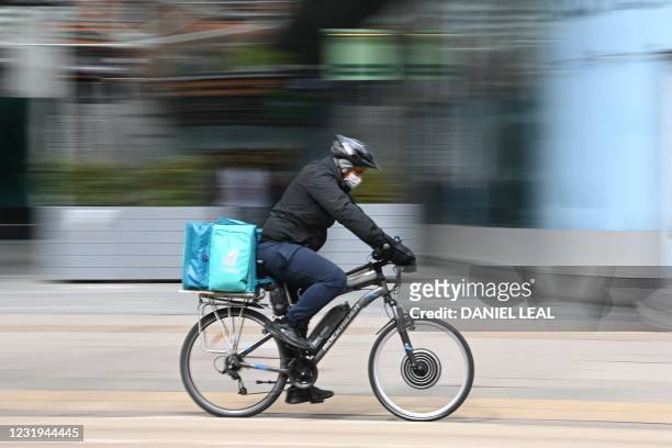 Deliveroo rider cycles through central London on March 26, 2021. - The meal delivery platform Deliveroo is bracing for strikes and other social...
